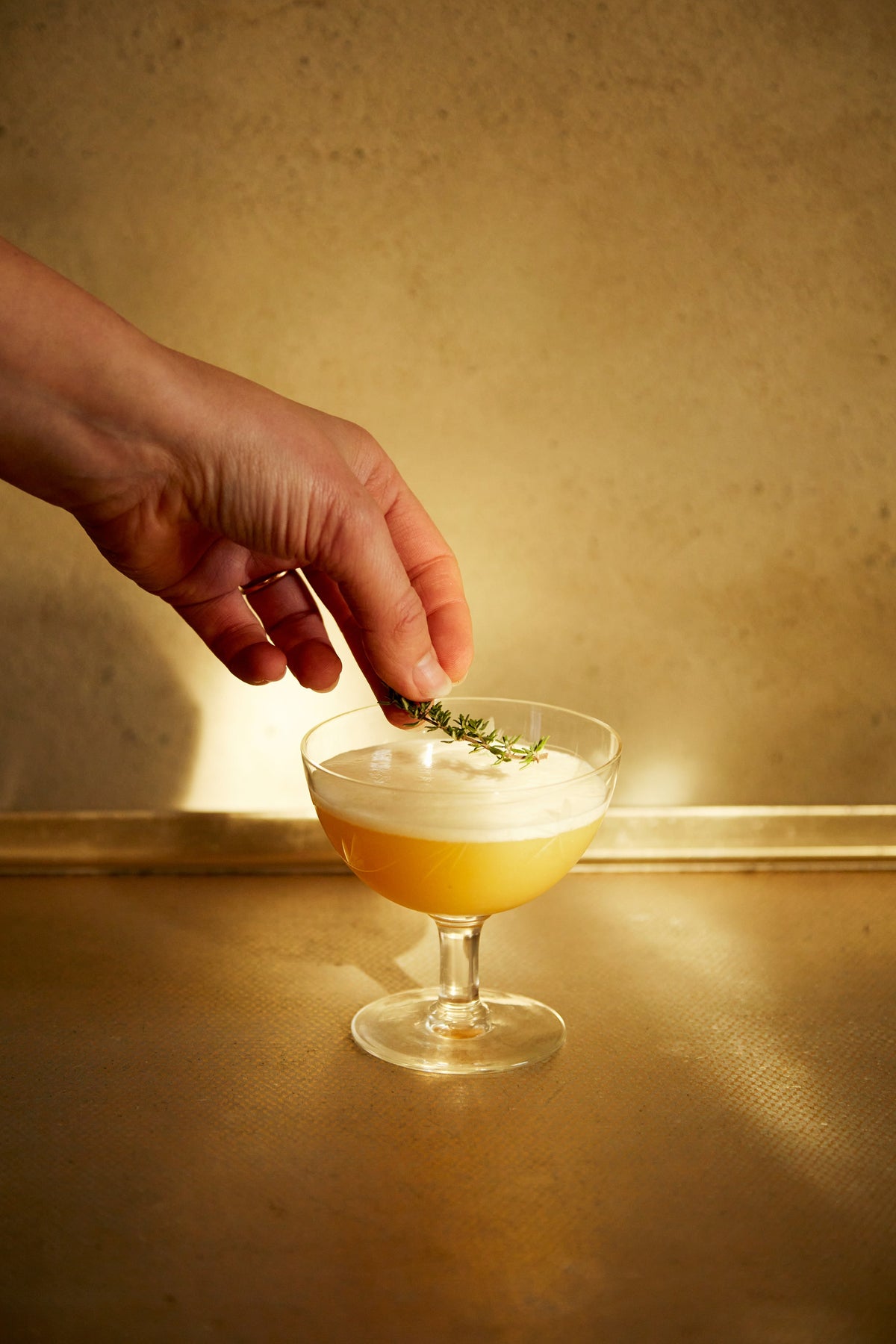 Hand placing rosemary on an egg white drink