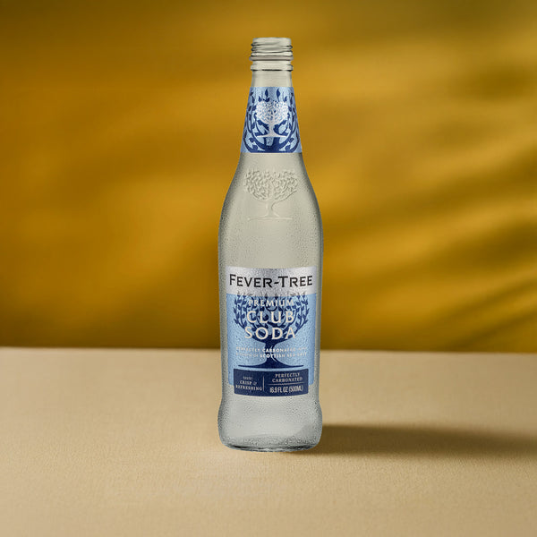 A chilled 16.9 fl oz Fever Tree Club Soda by Mother Root stands on beige with a golden mixer-ready backdrop.
