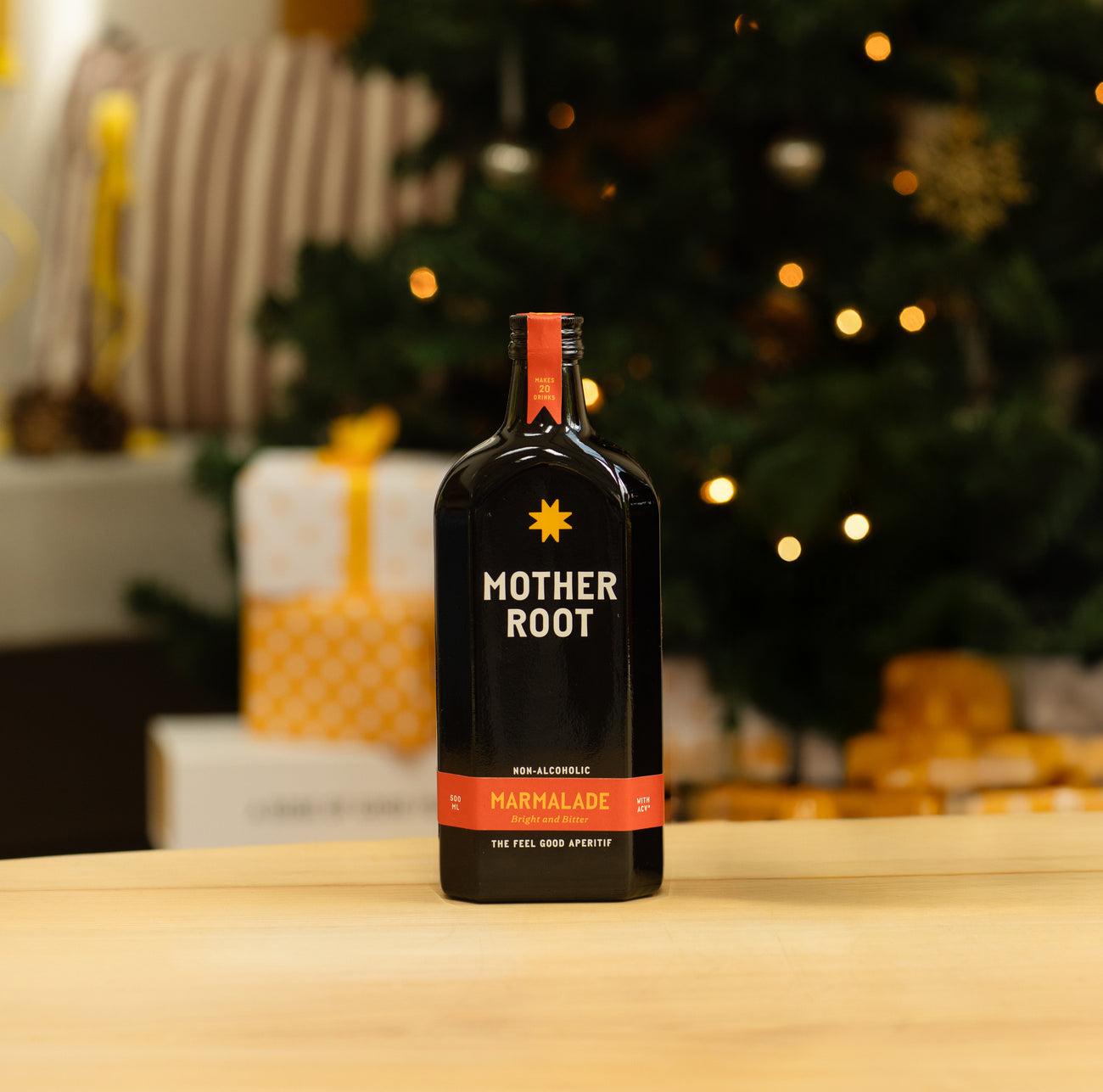 A bottle of Mother Root Marmalade (Limited Edition) sits on a table in front of a festive Christmas tree and gifts.