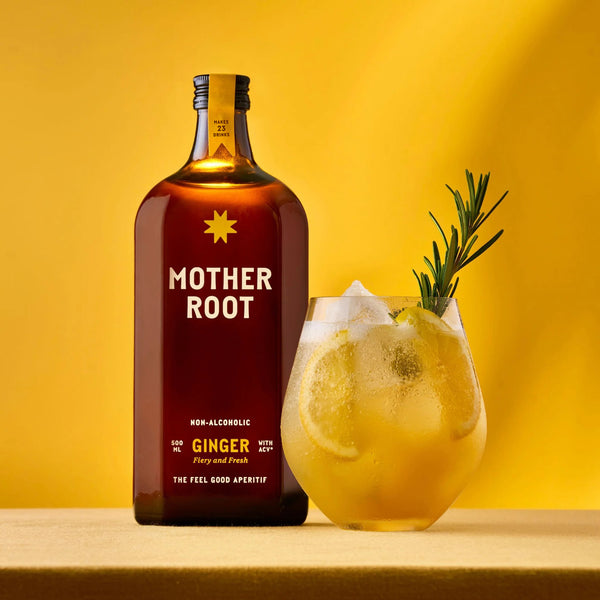 Brown bottle labeled "Mother Root Ginger" beside a glass of ice-filled yellow drink with lemon slices and rosemary on a yellow background.