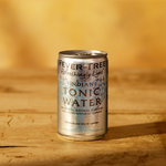 Fever tree refreshingly light tonic can on wooden table with yellow background