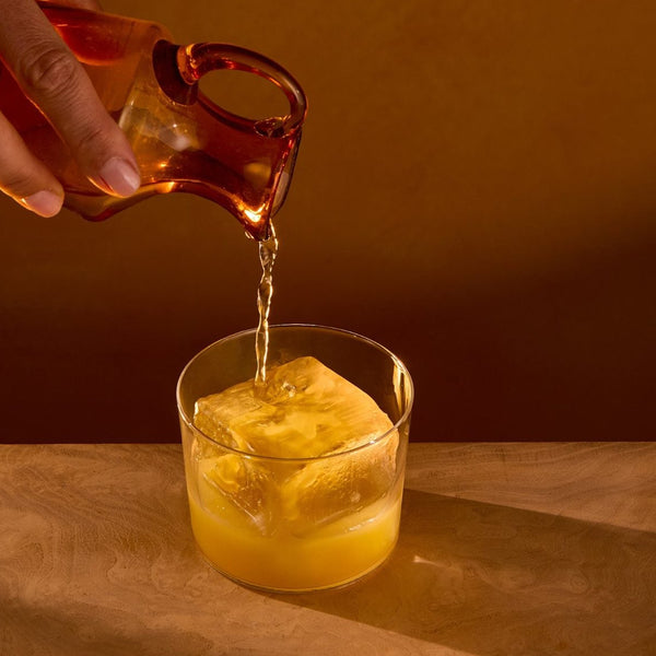 Topping the glass with still water from an amber jug